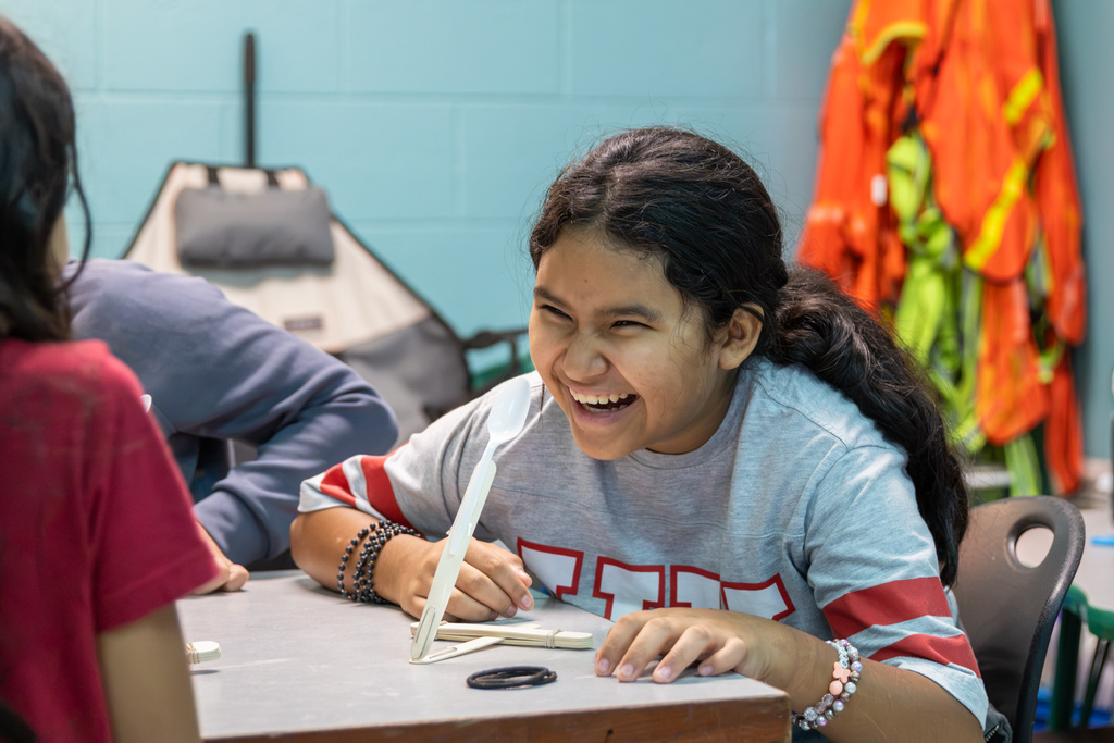 A Western Oaks Elementary student laughs while leaning toward her handmade catapult during a hands-on engineering activity.