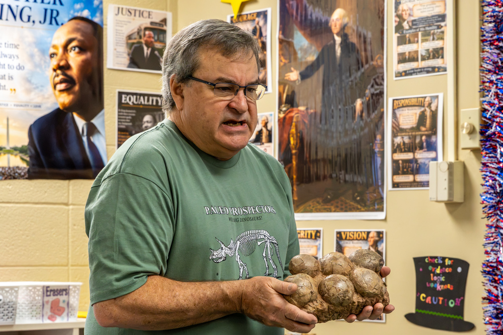 Dale Utt holds a large fossilized cluster of rounded dinosaur eggs while explaining the specimen to students at Dennis Elementary.