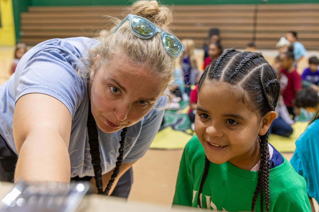 A presenter leans in close with a young Western Oaks Elementary student as they examine an observation bee frame together.