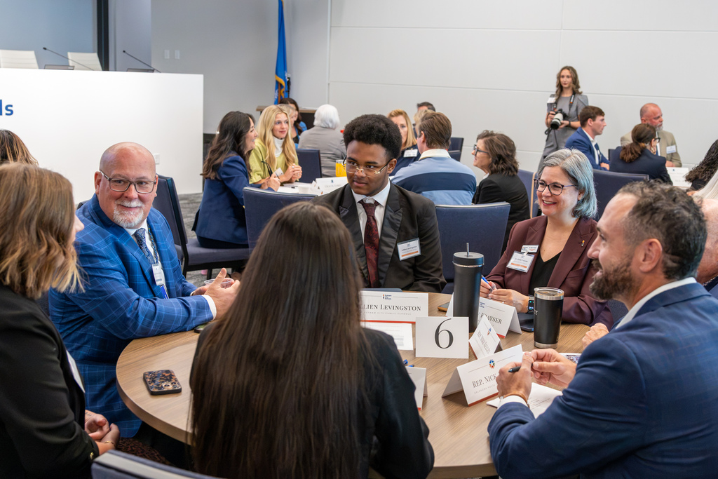 A student representative speaks at a table during small group discussions with district administrators and state representatives.
