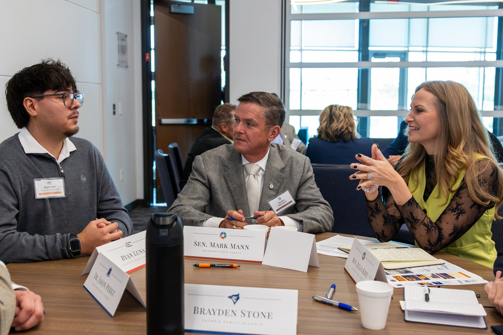 Putnam City student Ryan Luna sits at a small group round table in conversation with State Senator Mark Mann and State Senator Carrie Hicks.