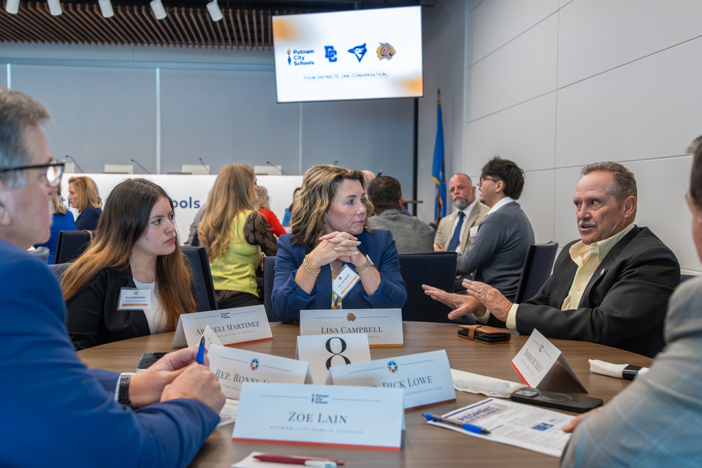 High school student Julien Levingston converses with local lawmakers and school administrators seated around a small group discussion table.