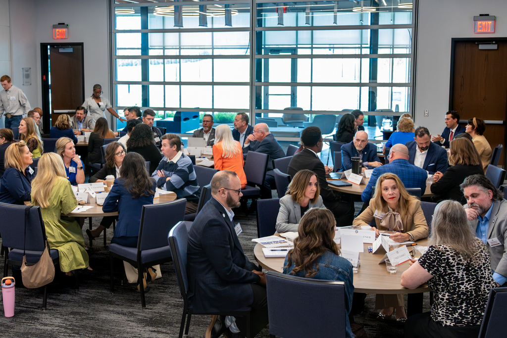 Wide view of the PC Centennial Center filled with round tables as students, educators, and state lawmakers participate in small group discussions.