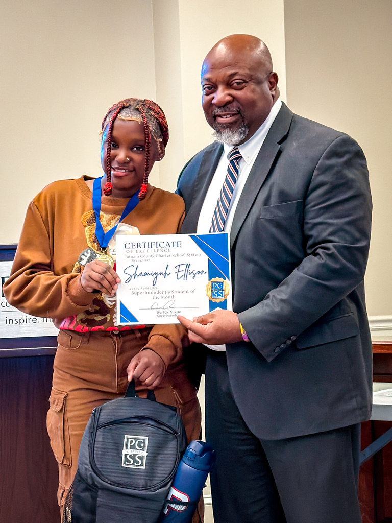 A man in a suit presents a certificate to a young woman with a backpack, both smiling.