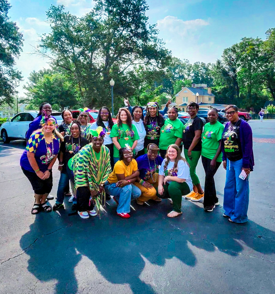 Group of people in green and yellow outfits pose for a photo in a parking lot.