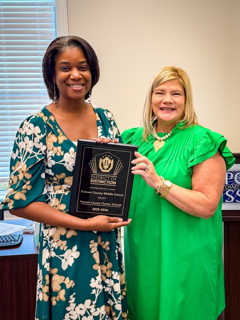 Two women in green dresses holding a plaque with the text "Pulaski County Middle School" and "2023-2024".