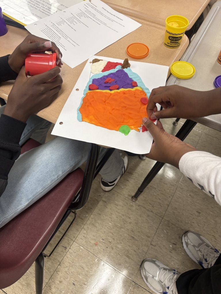 A person uses a red container for a craft project, while another person adjusts a paper with an orange and yellow creation.