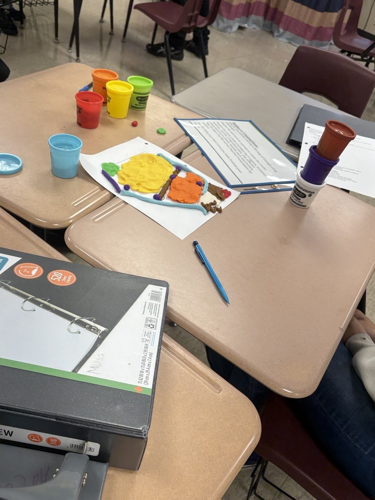 Tables with art supplies like paint cups, brushes, and papers. One table has a box labeled "NEW".