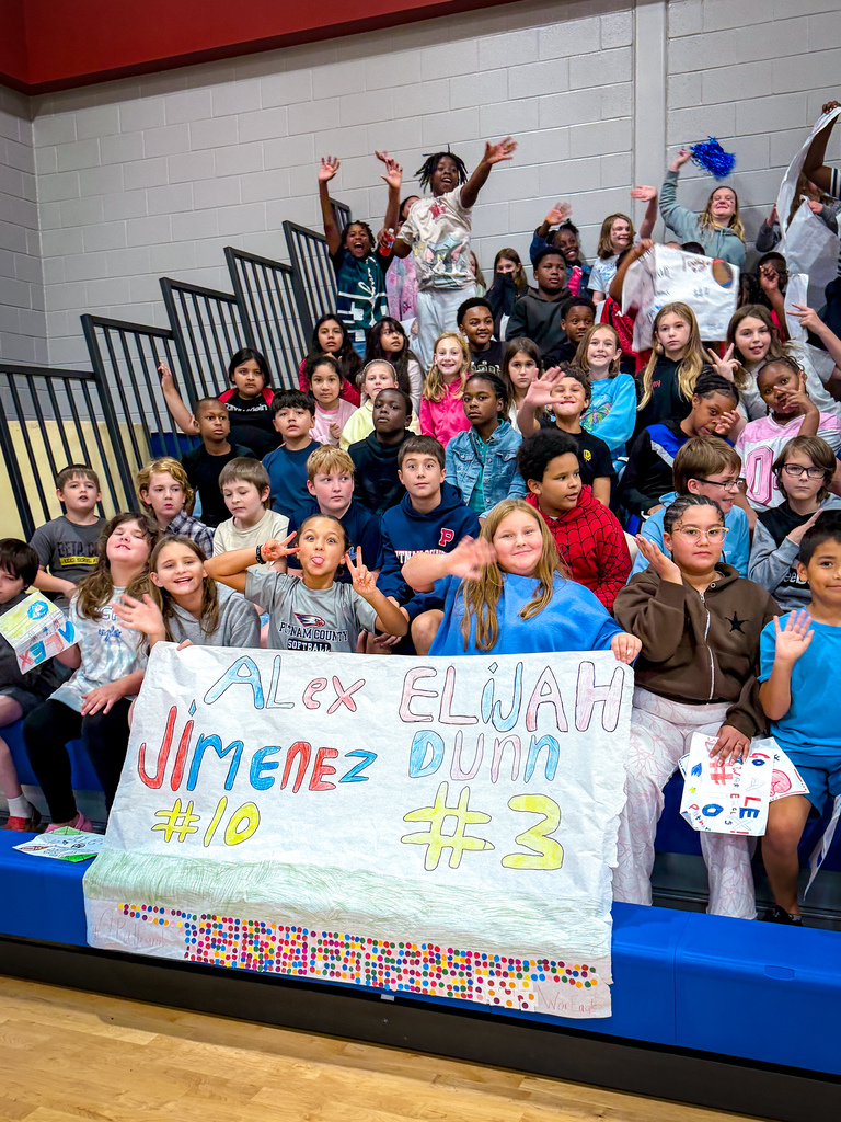 Group of children cheering with a banner that says Alex Jimenez #10 and Elijah Dunn #3.
