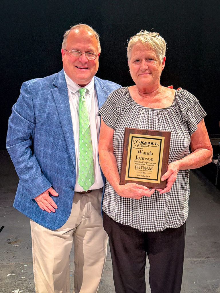A woman holds a plaque that reads "Wanda Johnson, Putnam" while standing next to a man.