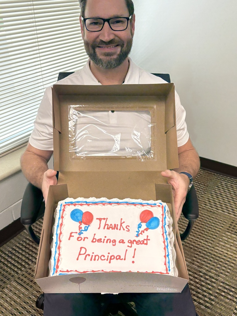 Mr. Patrick holding cake for Principal's Month celebration.