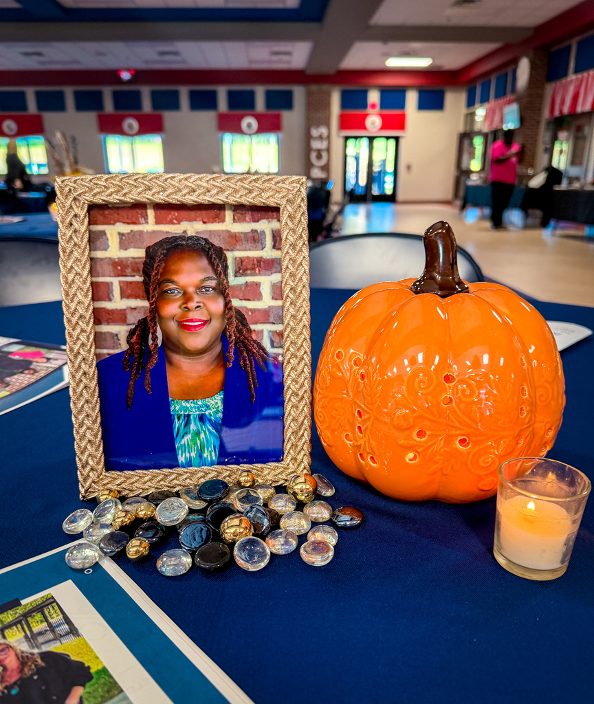 A blue table with a photo of a woman, a carved pumpkin, a candle, and a group of buttons.