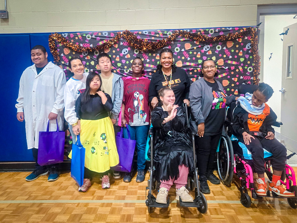 A group of students in costumes, standing and sitting in wheelchairs, posing for a photo.