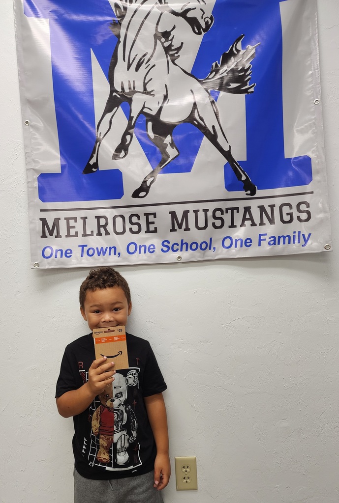 Male student holding a gift card under the Melrose Sign