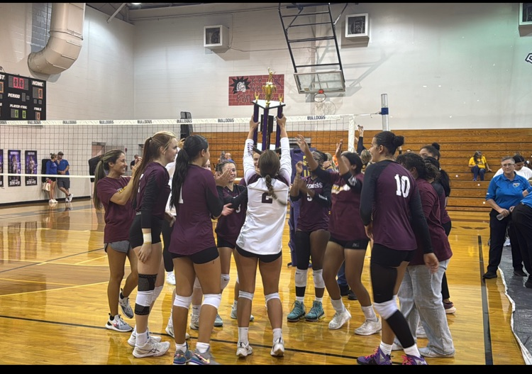 Volleyball team celebrating championship win with the trophy.