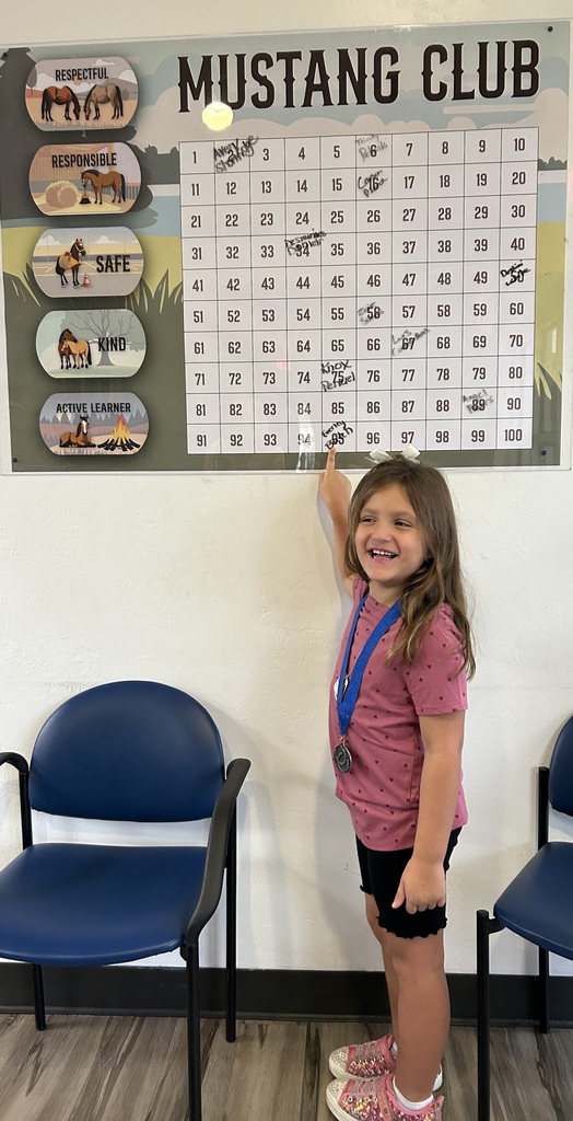 picture of girl in pink shirt pointing to Mustang Club board.