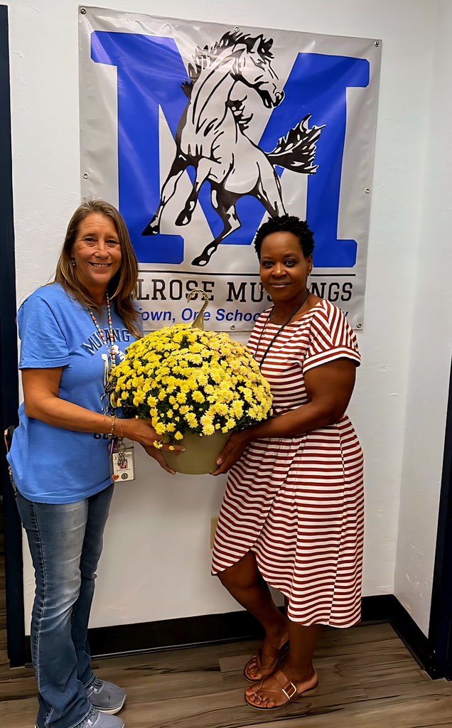 picture of 2 ladies holding flower in front of Mustang banner