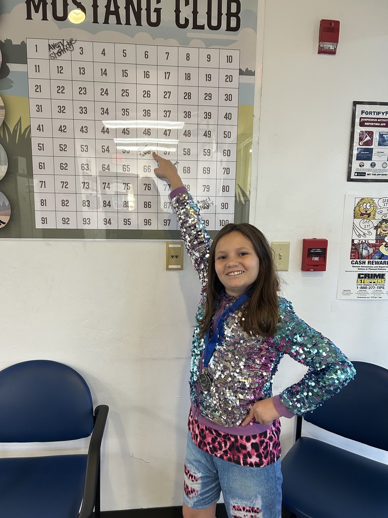 Picture of female student pointing at the Mustang Club board.