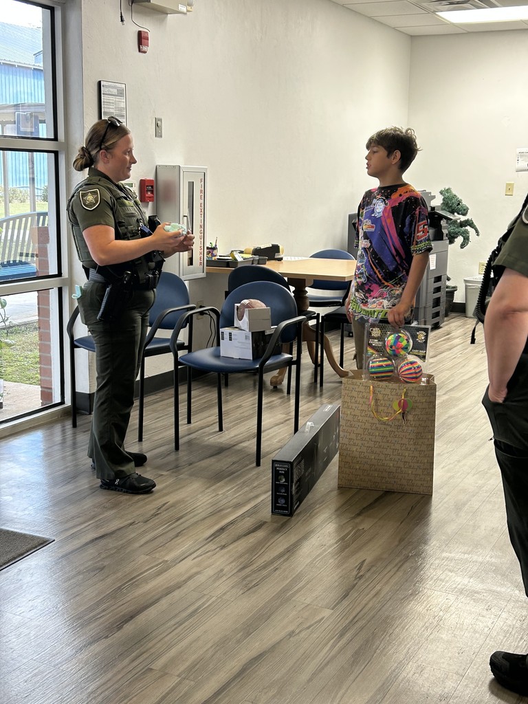 Picture of student opening a gift from sheriff deputies.