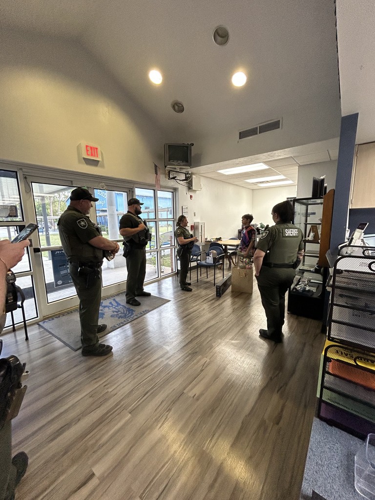 Picture of male student with 4 sheriff deputies giving him a birthday present.