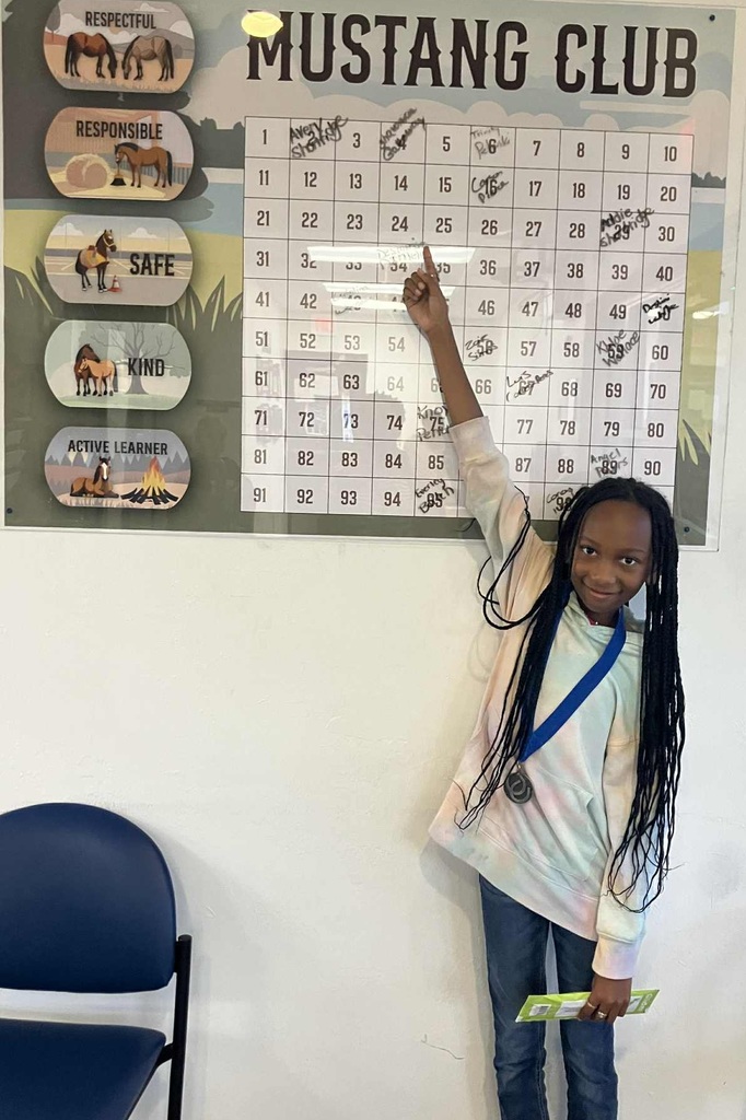 Picture of female student pointing at the Mustang Club board.