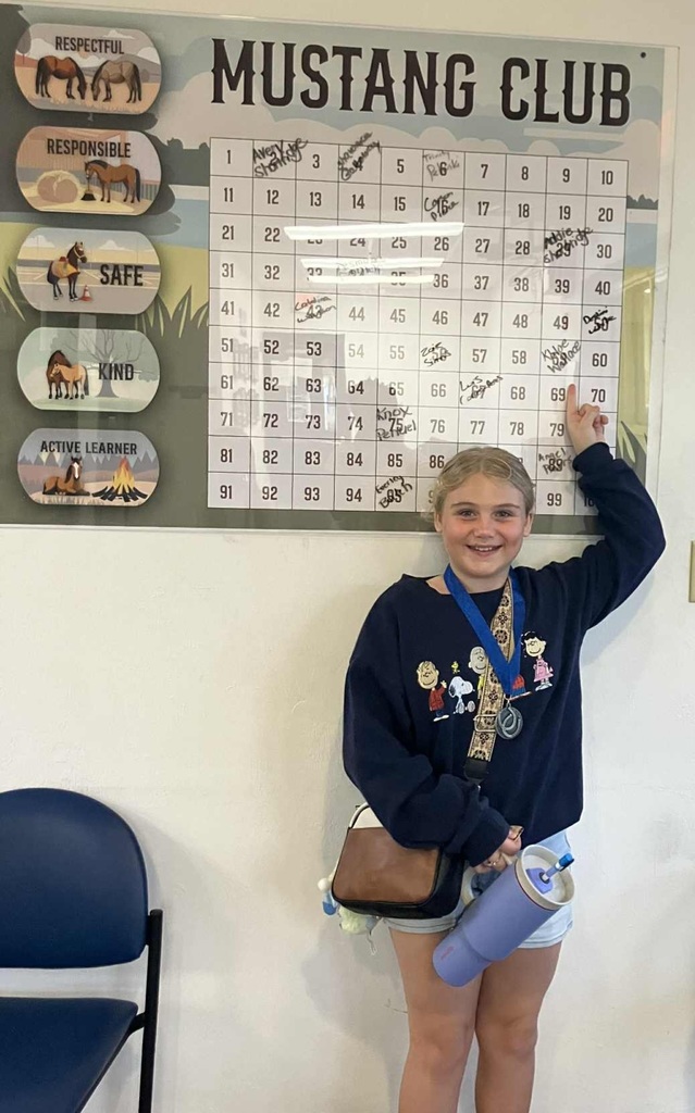 Picture of female student pointing at the Mustang Club board.