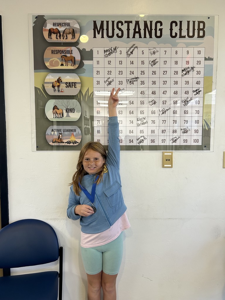 Picture of female student pointing at the Mustang Club board.