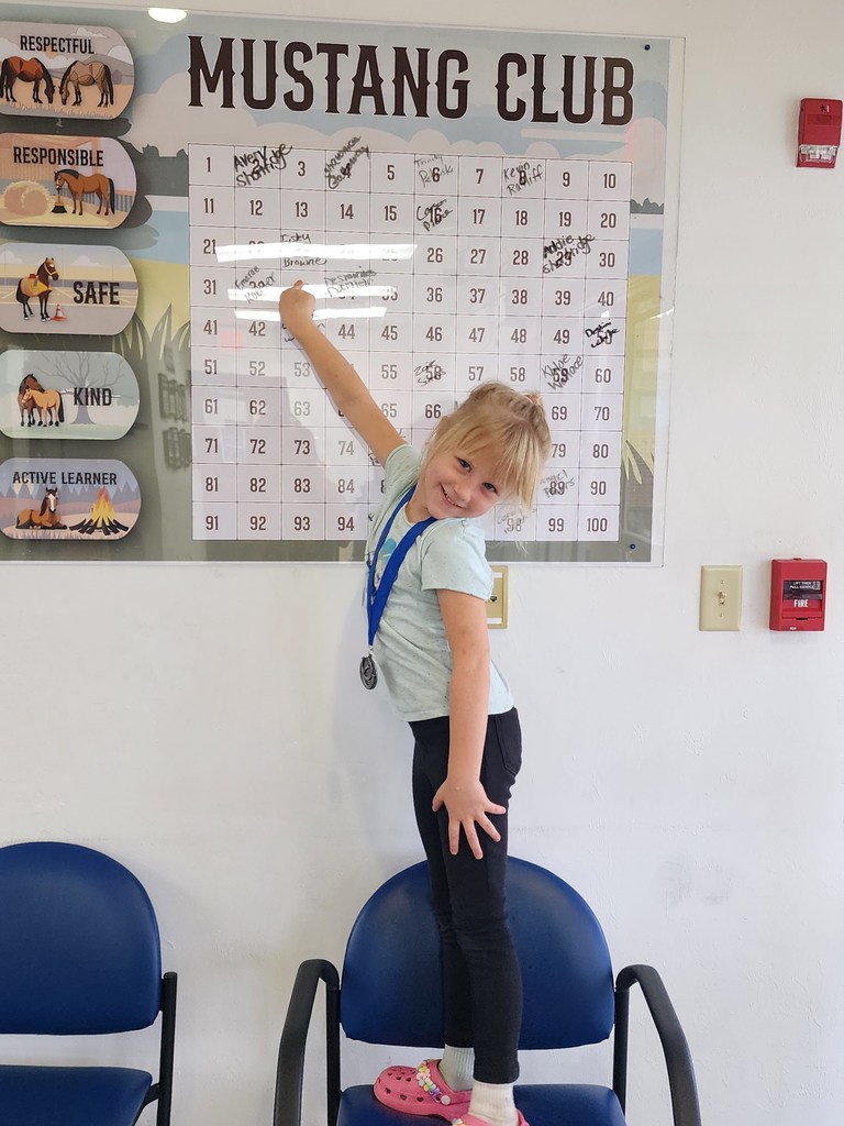 Picture of female student pointing at the Mustang Club board.