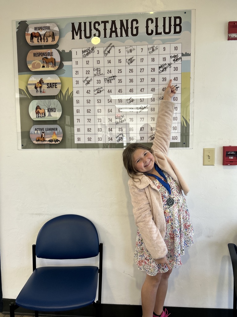 Picture of female student pointing at the Mustang Club board.
