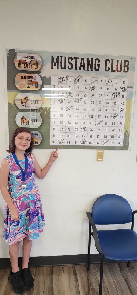 Picture of female student pointing to the Mustang Club board.
