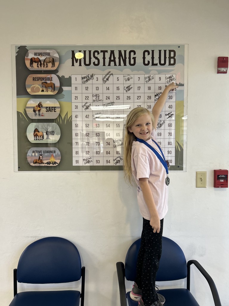 Picture of female student pointing to the Mustang Club board.