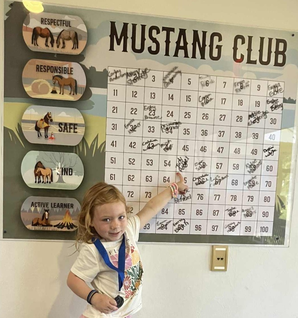 Picture of female student pointing at the Mustang Club board.