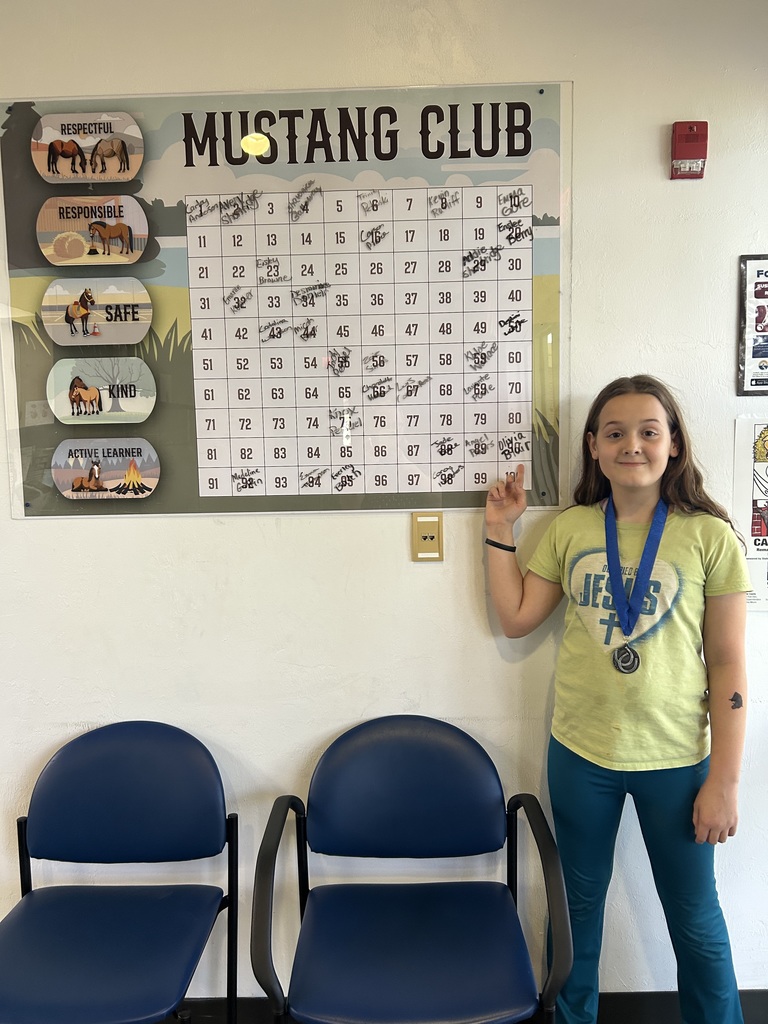 Picture of female student pointing at the Mustang Club board.