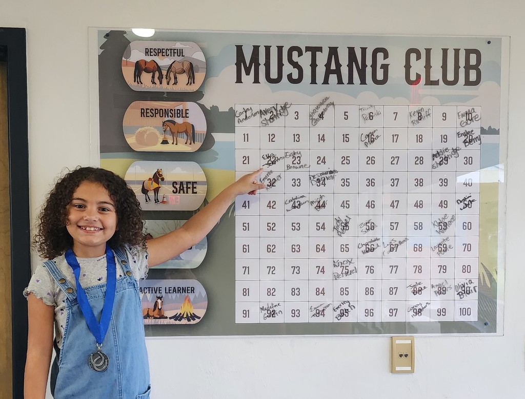 Picture of female student pointing at the Mustang Club board.