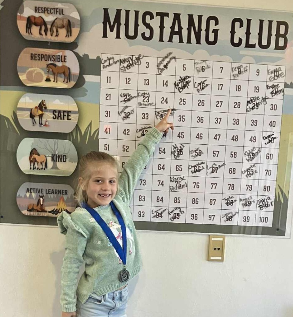 Picture of female student pointing at the Mustang Club board.