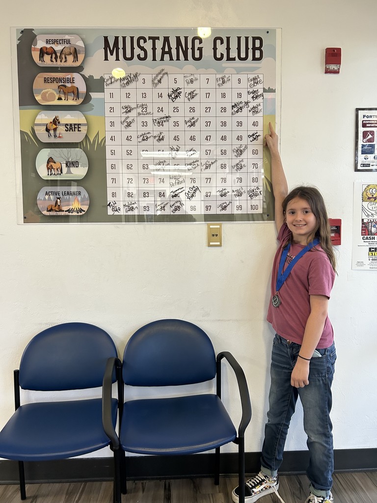 Picture of female student pointing at the Mustang Club board.