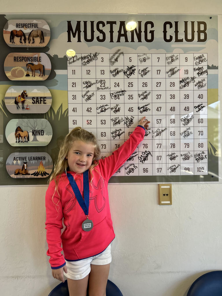 Picture of female student pointing at the Mustang Club board.