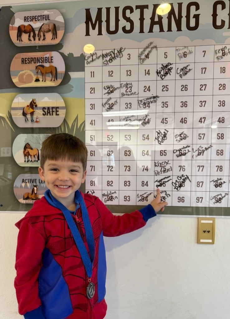 picture of male student pointing at Mustang Club board