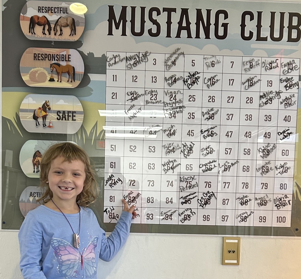 Picture of female student pointing at the Mustang Club board.