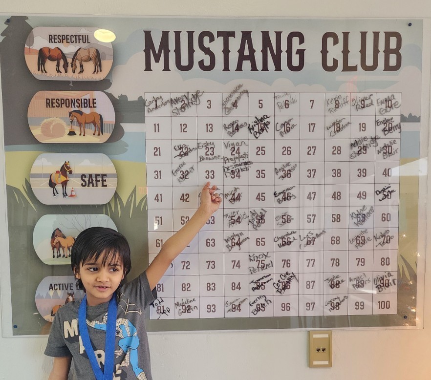 picture of male student pointing at Mustang Club board