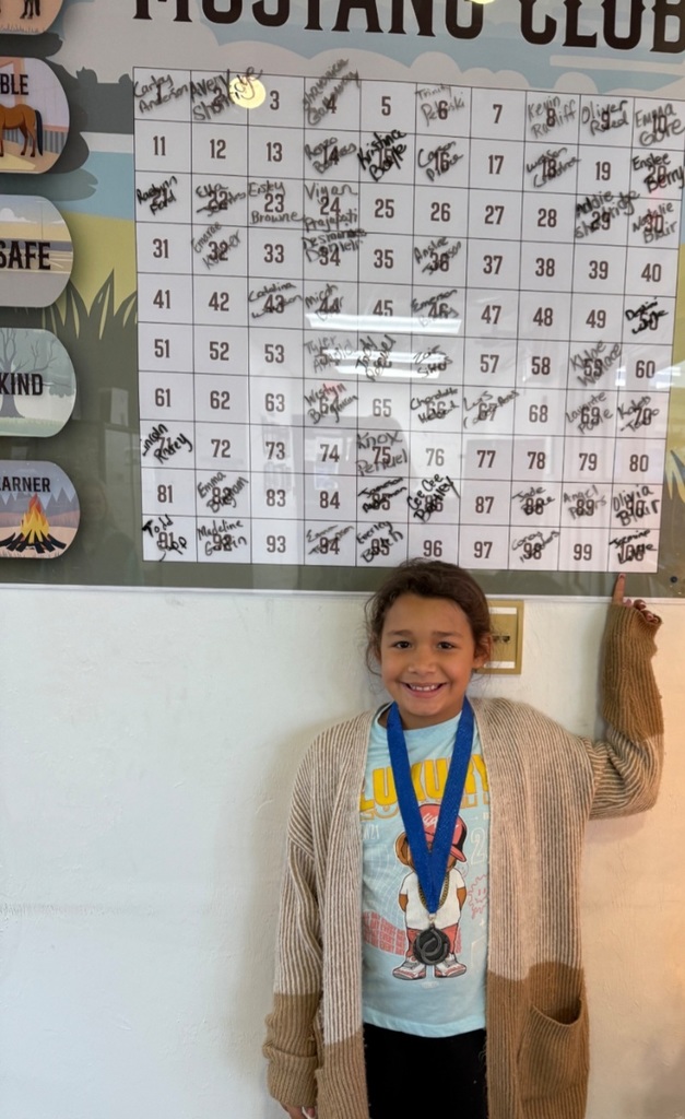 picture of female student pointing to Mustang Club board