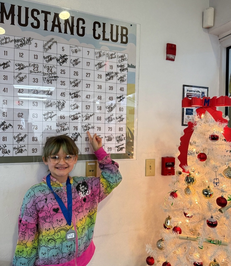 Picture of female student pointing at the Mustang Club board.