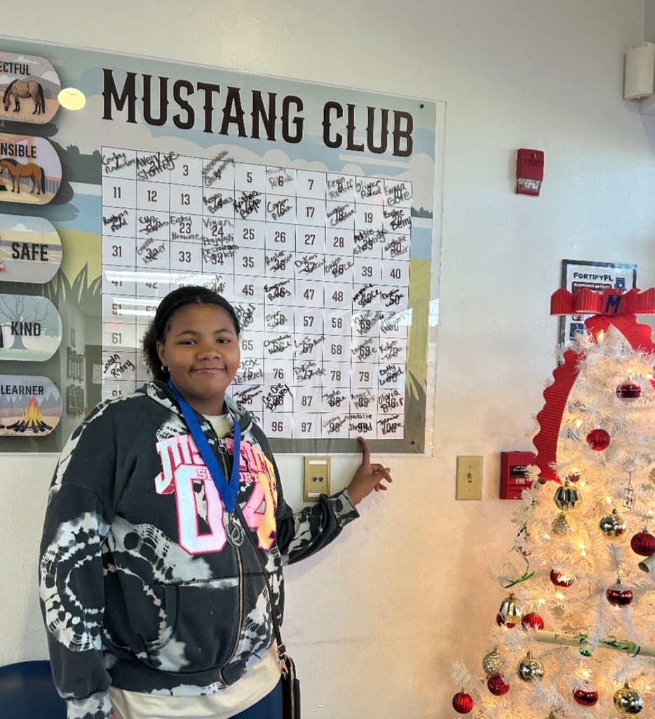 picture of female student pointing to Mustang Club board