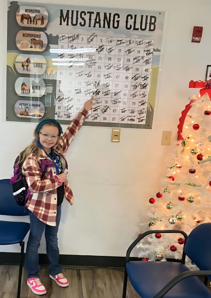 Picture of female student pointing at the Mustang Club board.