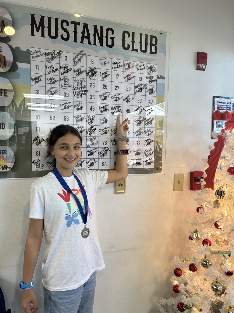 Picture of female student pointing at the Mustang Club board.