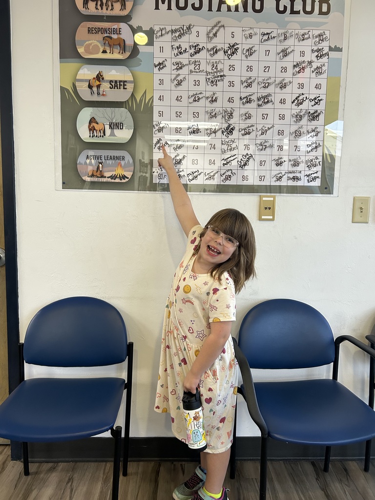 Picture of female student pointing at the Mustang Club board.
