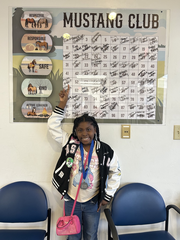 Picture of female student pointing at the Mustang Club board.