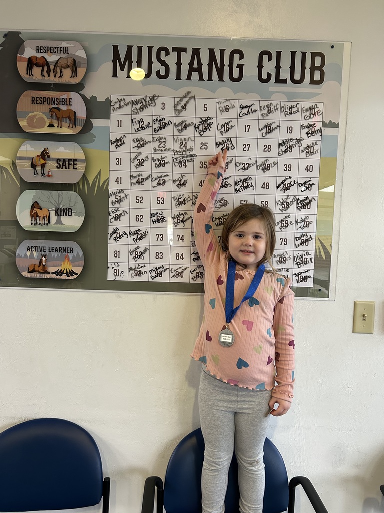 Picture of female student pointing at the Mustang Club board.
