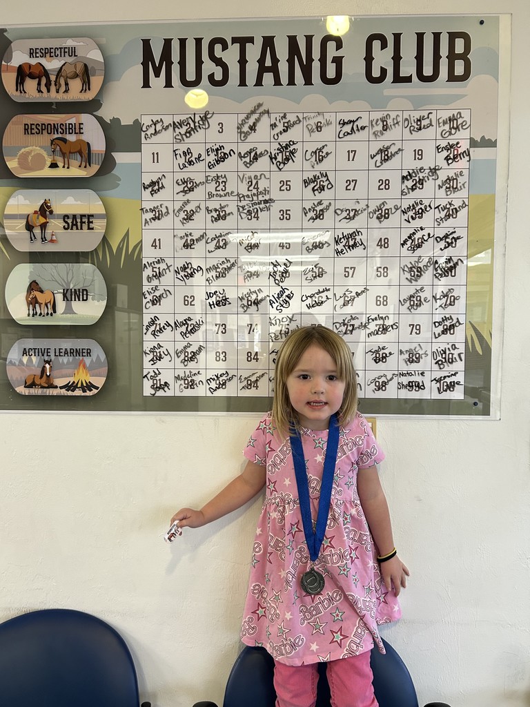 Picture of female student pointing at the Mustang Club board.