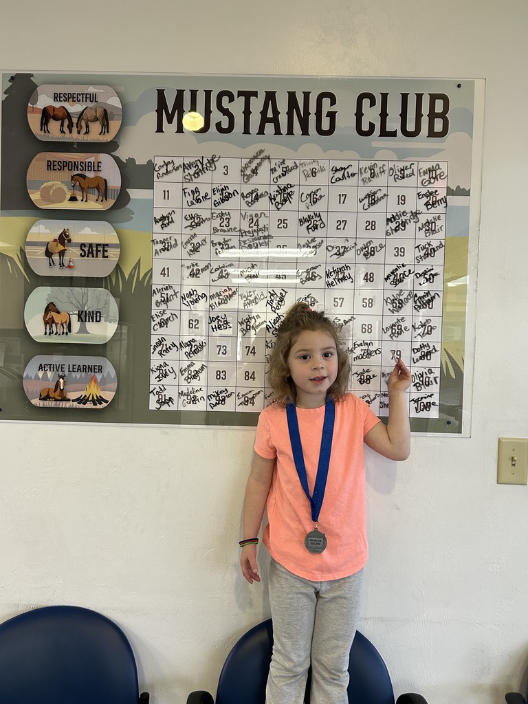 Picture of female student pointing at the Mustang Club board.